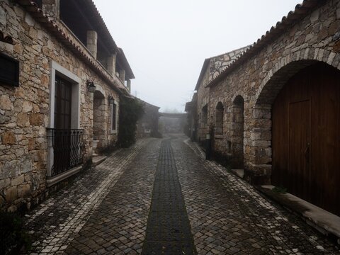 Old historic traditional stone buildings exterior house facade in dense fog mood Pia do Urso Batalha Portugal Europe