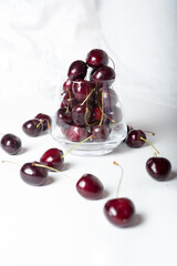 Sweet ripe cherries in  glass bowl around white background