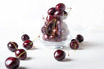 Sweet ripe cherries in  glass bowl around white background