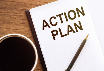 ACTION PLAN text on notepad on wooden desk.