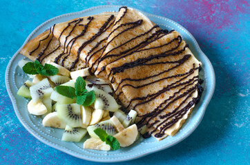 Delicious pancakes for breakfast with fruit and chocolate