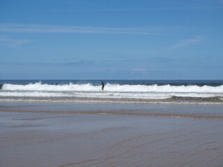 Paisaje de costa con windsurfistas sobre las olas de la Playa el Rosal en Cantabria, verano de 2020