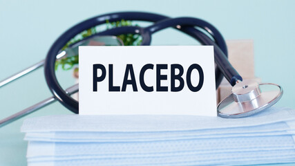card with word placebo, stethoscope, face masks and flower on table