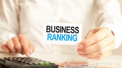 A woman a holding piece of paper with the text: BUSINESS RANKING. Finance and economics concept.