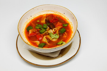 Spicy soup in a deep plate on a white background