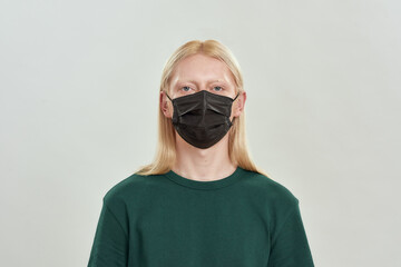 Serious young caucasian man wearing protective mask