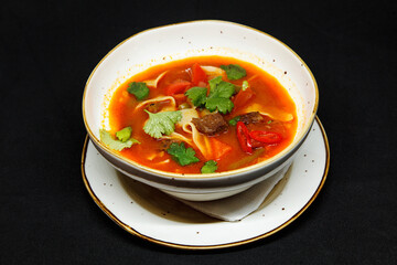Spicy soup in a deep plate on a black background