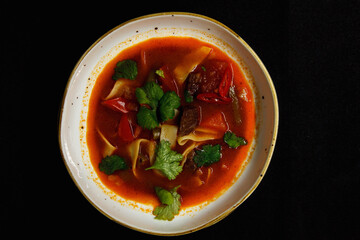 Spicy soup in a deep plate on a black background