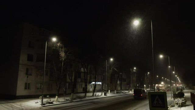 intersectie luminata cu masini &icirc;n oraș &icirc;n noaptea de iarnă cu zăpadă