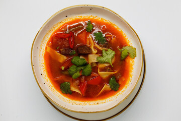 Spicy soup in a deep plate on a white background