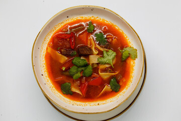 Spicy soup in a deep plate on a white background