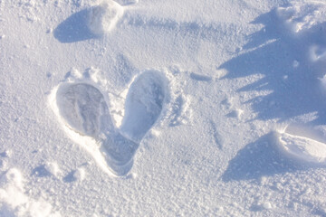 Top view, closeup couple's deep footprint in heart shape on pure soft white snow, natural sunlight in the winter season. Romantic outdoor message idea for Valentine's day, beautiful symbol of love ]