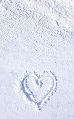 Hand drawn of a heart shape on natural pure bright white soft snow surface in cold weather in the winter season, a symbol of love. A romantic idea for Valentine's day. Vertical banner with copy space.