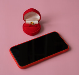 New smartphone and engagement ring in red gift box on pink background. The concept of best gift for...