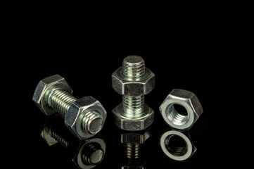 Metal bolts and nuts on a black isolated background is used in construction to connect parts