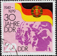 GERMANY, DDR - CIRCA 1979 : a postage stamp from Germany, GDR showing Faces of a worker, Soviet soldier in front of the flag of the GDR: 30 years of the GDR