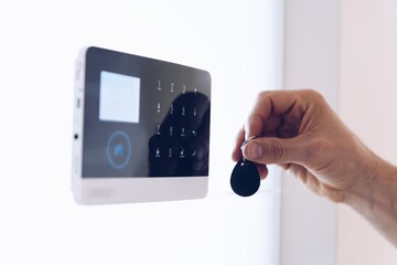 Home remote control alarm. The hand with the remote control disarms the security system.