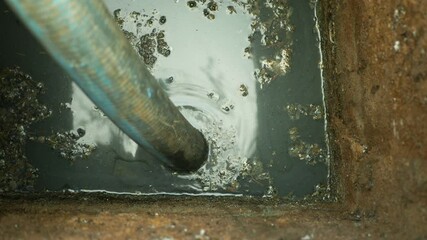 Cesspool pipe septic emptying pumping into tank by suction hose under high pressure. The sump contains pollution sludge sewage water black wastewater and faeces plus excrements from home