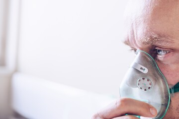 Sick patient man breathing with oxygen mask in hospital