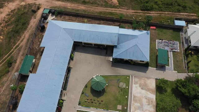 Aerial orphanage rural Ghana descend into yar. Homes, apartment, playgrounds, library and facilities to help young boys and girls escape slave and child labor. Volunteer facility. Tropical forest land
