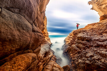 Long exposure landscape of the cave, sea and a woman with umbrella in Akyar, Silifke, Mersin,...