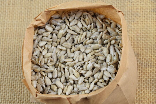 Sunflower seeds in paper bag closeup, gluten free healthy seeds, on jute fabric background
