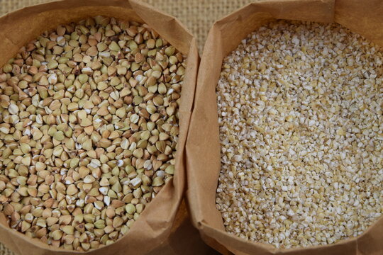 Buckhwheat unroasted and pearl barley closeup, healthy groats in apper bags on jute fabric background