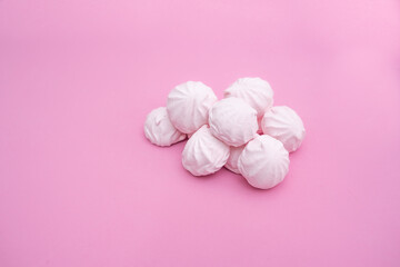 A bunch of small marshmallows on a pink background