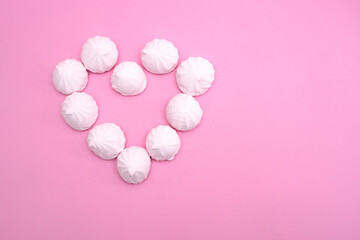 The heart is lined with small marshmallows on a pink background. Background for valentine's day.
