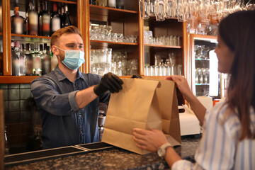 Waiter giving packed takeout order to customer in restaurant. Food service during coronavirus quarantine