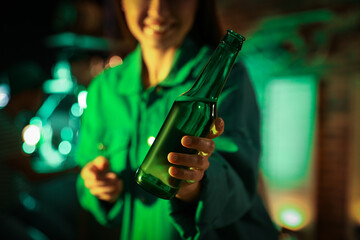 Woman with beer celebrating St Patrick's day in pub, focus on hand