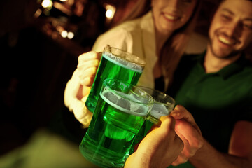 People with beer celebrating St Patrick's day in pub, focus on hands