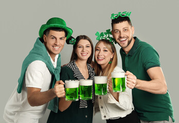 Happy people in St Patrick's Day outfits with beer on light grey background