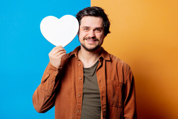 Guy in shirt hold heart shape banner on yellow and blue background