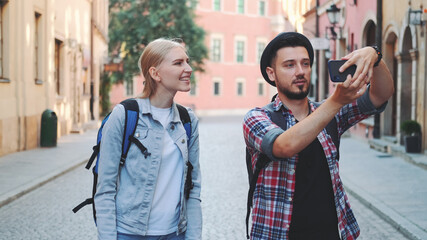 Young tourist couple walking on the street and making photos on smartphone. They admiring the beauty of surroundings.