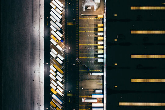 Aerial view of the trucks unloading at the logistic center. Night view with a bit of snow.