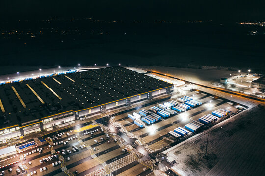 Aerial view of the trucks unloading at the logistic center. Night view with a bit of snow.