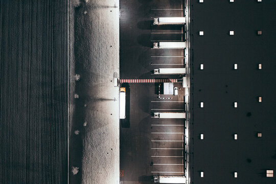 Aerial view of the trucks unloading at the logistic center. Night view with a bit of snow.