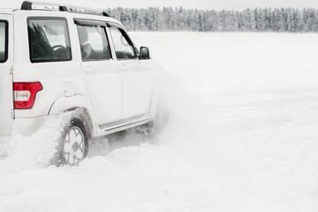 Modern white Suv car on snowy road when driving through snowdrifts. Four wheel drive car. Driving in the dangerous conditions in winter, snow drifting. Winter tires test