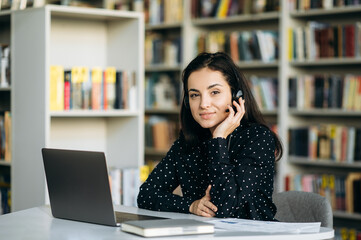 Confident business lady sit in modern office, smiling. Caucasian successful woman wearing headset, working in support service, consulting people