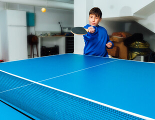 Boy playing table tennis with blue sweater