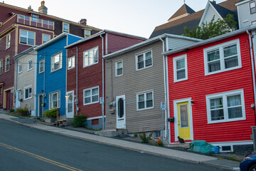St. John's, NL Canada-January 2021:A row of colourful wooden houses on a small narrow street in St. John's, Newfoundland with sidewalks and pavement exposed on a steep hill.