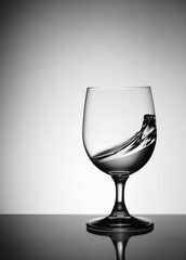 transparent wine glass with splashing liquid inside