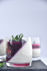 Delicious home made dessert panna cotta with berry sauce, fresh berries and mint in glasses