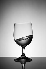 transparent wine glass with splashing liquid inside