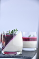 Delicious home made dessert panna cotta with berry sauce, fresh berries and mint in glasses