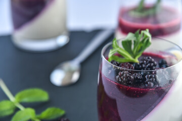 Delicious home made dessert panna cotta with berry sauce, fresh berries and mint in glasses