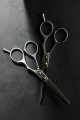 Metallic barber scissors on top of dark background.
