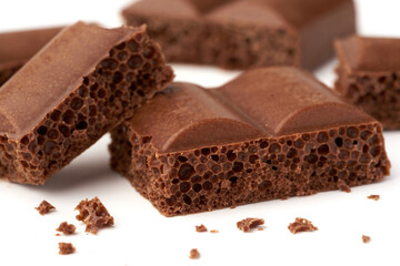 Close-up of a pieces of aerated milk chocolate isolated on white background