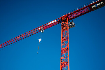 Red construction crane on bright blue sky